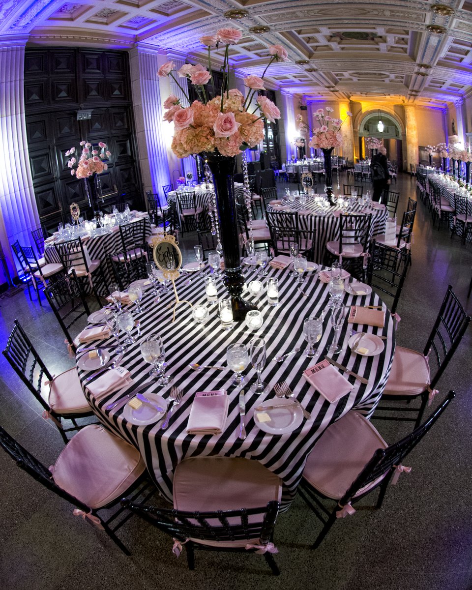 Ballroom tables with striped linens and pink floral arrangements